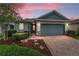 Charming single-story home with a brick driveway, well-manicured landscaping, and a two-car garage, set against a beautiful dusk sky at 5651 Nw 40Th Pl, Ocala, FL 34482