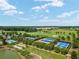 Aerial view of tennis courts and pool featuring well maintained landscaping with a view of the wider community at 5651 Nw 40Th Pl, Ocala, FL 34482