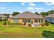 Aerial view of backyard with stone patio, dining set, manicured lawn, and lush landscaping at 6683 Sw 97Th Terrace Rd, Ocala, FL 34481