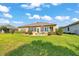 Backyard view featuring a stone patio with an outdoor dining set, flower beds, and a lush green lawn at 6683 Sw 97Th Terrace Rd, Ocala, FL 34481