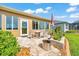 Stone patio with an outdoor dining set, flower beds, a stainless steel fire pit, and well-maintained grass at 6683 Sw 97Th Terrace Rd, Ocala, FL 34481