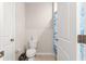 Cozy half bathroom with a toilet, paper holder and a white door with a blue curtain at 8142 Sw 59Th Ave, Ocala, FL 34476