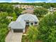 Aerial view of a single-story home with a gray roof, green lawn, mature trees, and an attached garage at 8961 Se 130Th Loop, Summerfield, FL 34491