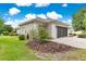 Exterior view of a home's side with a large garage door, landscaping, and well-maintained lawn at 8961 Se 130Th Loop, Summerfield, FL 34491