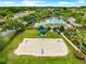 Aerial view of a sand volleyball court and a swimming pool with lounge chairs in the background at 8961 Se 130Th Loop, Summerfield, FL 34491
