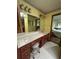 Comfortable bathroom with a long vanity counter and wood drawers, chair, mirror, and lighting at 9622 Se 71St Ct, Ocala, FL 34472