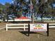 Leeward Air Ranch Red Barn Community Center featuring a sign, flagpole, and white fence at 9622 Se 71St Ct, Ocala, FL 34472