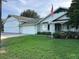 Charming single-story home with a lush green lawn and a three car garage with an American flag at 9622 Se 71St Ct, Ocala, FL 34472