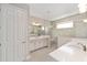 Bright bathroom featuring double sinks, tiled shower with frameless glass, and white cabinets at 9865 Sw 105Th Ct, Ocala, FL 34481