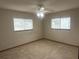 Carpeted bedroom with a ceiling fan and two windows overlooking a neighborhood street at 11248 Sw 76Th Ter, Ocala, FL 34476