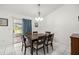 Bright dining room featuring white tile flooring, a modern chandelier, and sliding glass doors to the outside at 12 Hemlock Radial Pass, Ocala, FL 34472