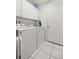Convenient laundry room with white appliances, ample storage, and tile flooring, perfect for household chores at 12 Hemlock Radial Pass, Ocala, FL 34472
