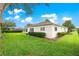 Exterior back of home featuring well-maintained yard, manicured landscaping, and mature trees at 13715 Se 88Th Ct, Summerfield, FL 34491