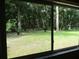 View through a glass door showcasing a lush backyard with mature trees and green grass at 14192 Sw 112Th Cir, Dunnellon, FL 34432