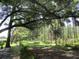 Lush backyard featuring mature trees and an expansive green space with a rustic fence-lined path at 14192 Sw 112Th Cir, Dunnellon, FL 34432