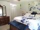 Comfortable bedroom featuring a large bed with a blue floral comforter, antique dresser, and ample closet space at 14192 Sw 112Th Cir, Dunnellon, FL 34432