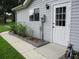 Exterior side entrance featuring a white door, gray vinyl siding, and manicured landscaping at 14192 Sw 112Th Cir, Dunnellon, FL 34432