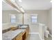 Bright bathroom featuring dual sinks, decorative framed mirror, and tile flooring at 145 Harbor Way, Auburndale, FL 33823