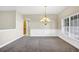 Light-filled dining room featuring gray carpet, neutral walls, and elegant chandelier fixture at 145 Harbor Way, Auburndale, FL 33823