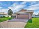 Paver driveway leading to a two car garage with manicured lawn and landscaping under a bright, partly cloudy sky at 145 Harbor Way, Auburndale, FL 33823