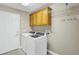 Practical laundry room features a washer, dryer, and overhead cabinets for storage at 145 Harbor Way, Auburndale, FL 33823