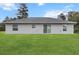 The back of this single-story home features a well-kept lawn, three windows, and a sliding glass door at 17277 Sw 44Th Cir, Ocala, FL 34473