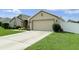 Neutral home with a wide driveway, two-car garage, manicured lawn, and white picket fence at 186 Nw 44Th St, Ocala, FL 34475