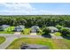 Aerial view of three homes in a neighborhood featuring manicured lawns and lush green trees at 19551 Sw 77Th Loop, Dunnellon, FL 34432