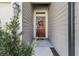 Close-up of a home's entryway with a decorative wreath on a wooden door and light fixture at 19551 Sw 77Th Loop, Dunnellon, FL 34432