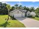 Beautiful home exterior featuring a three-car garage, green lawn and mature palm trees at 19551 Sw 77Th Loop, Dunnellon, FL 34432