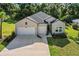Well-manicured home exterior showcasing a three-car garage, lush landscaping and a charming entryway at 19551 Sw 77Th Loop, Dunnellon, FL 34432