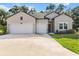 Beautiful home featuring a spacious driveway, light gray siding, double garage, and manicured lawn at 19551 Sw 77Th Loop, Dunnellon, FL 34432
