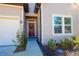 Inviting front entryway with a dark wood door with a wreath and beautiful landscaping at 19551 Sw 77Th Loop, Dunnellon, FL 34432