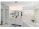 Bright bathroom featuring double sinks, a soaking tub with a glass block window, and white cabinets at 2644 Sw 20 Cir, Ocala, FL 34471