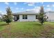 View of the backyard with a covered patio and well-manicured lawn, framed by lush trees and a clear blue sky at 32 Hickory Course Loop, Ocala, FL 34472