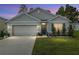 Well-lit home exterior featuring a manicured lawn and two car garage at 32 Hickory Course Loop, Ocala, FL 34472