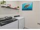Modern laundry room with newer appliances, shelving and turtle artwork at 32 Hickory Course Loop, Ocala, FL 34472