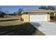 Two car garage with a large driveway and green yard around a yellow home at 360 Marion Oaks Golf Way, Ocala, FL 34473