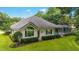 Beautiful single-story home showcasing a large window, manicured landscaping, and a screened-in pool enclosure at 7915 Se 12Th Cir, Ocala, FL 34480