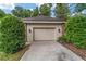 Attached two-car garage with beautiful curb appeal, surrounded by mature trees and greenery at 7915 Se 12Th Cir, Ocala, FL 34480