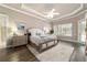 Bright main bedroom featuring an ensuite bathroom, wood floors, tray ceiling, and access to the outdoors at 7915 Se 12Th Cir, Ocala, FL 34480