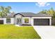 Charming single-story home featuring modern gray accents, black framed windows, and a manicured front lawn at 8456 Se 164Th Pl, Summerfield, FL 34491