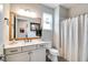 Bathroom featuring a modern vanity with a light countertop, a rustic wood-framed mirror, and a shower with a linen curtain at 9886 Sw 104Th Ave, Ocala, FL 34481
