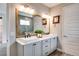 Bathroom with double vanity, a large framed mirror, wood-look flooring, and white paneled doors at 9886 Sw 104Th Ave, Ocala, FL 34481