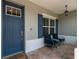 Inviting front porch with comfortable blue seating, brick pavers, and a beautifully colored door at 9886 Sw 104Th Ave, Ocala, FL 34481