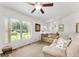 Bright living room with neutral tones, ceiling fan, and large window overlooking the front yard at 106 Pine Trce, Ocala, FL 34472