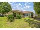 Home exterior showcasing well-maintained lawn with beautiful lush plants and a sunroom at 11326 Se 175Th Pl, Summerfield, FL 34491