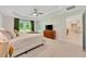 This main bedroom features a tray ceiling, ceiling fan, neutral carpet, and view of the backyard at 130 Nw 113Th Cir, Ocala, FL 34482