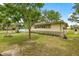 Exterior view showing a ramp, vinyl siding, and a well-maintained lawn with mature trees at 22535 Sw 117Th St, Dunnellon, FL 34431