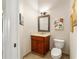 Half bath featuring a single vanity, toilet, tile flooring, and custom framed mirror and artwork at 3986 Se 43Rd Cir, Ocala, FL 34480